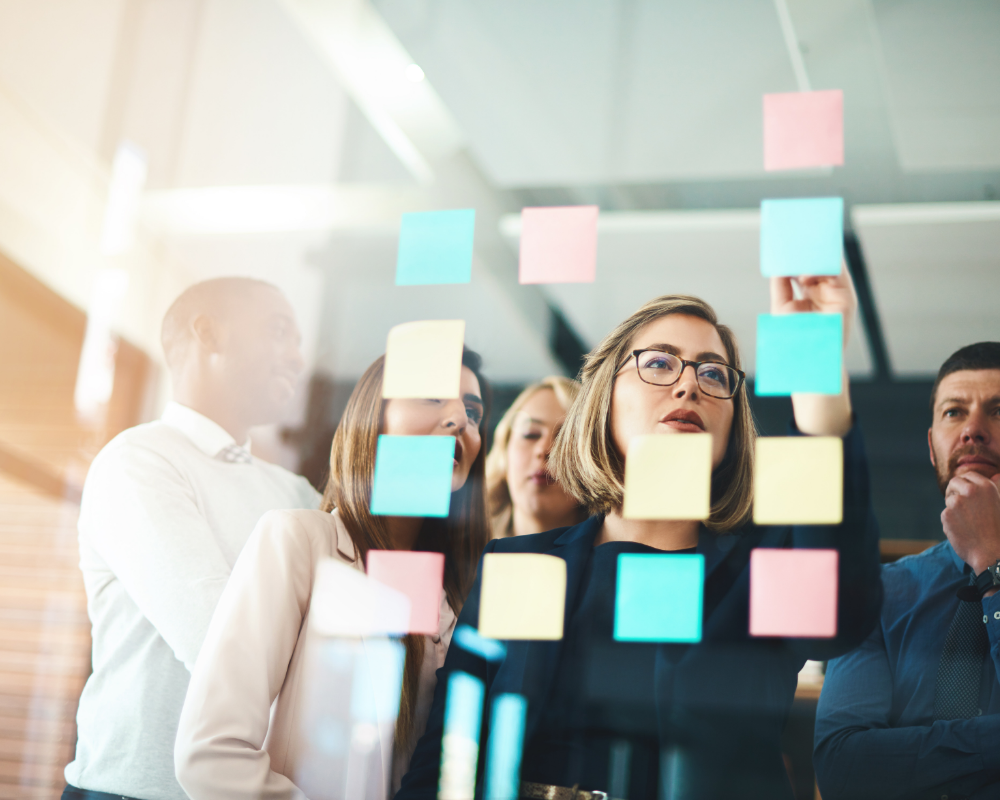 a group of people looking at sticky notes on a glass wall