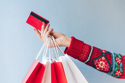 Image illustrant une main avec des sacs et une carte de crédit, représentant les achats de Noël.