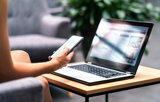 Wifi pour le travail à distance dans un salon-bar d'aéroport, un hall d'hôtel ou un café. Téléphone et ordinateur portable. Femme utilisant un smartphone et un ordinateur portable moderne sur une table. Agent immobilier ou étudiant lisant ses courriels.