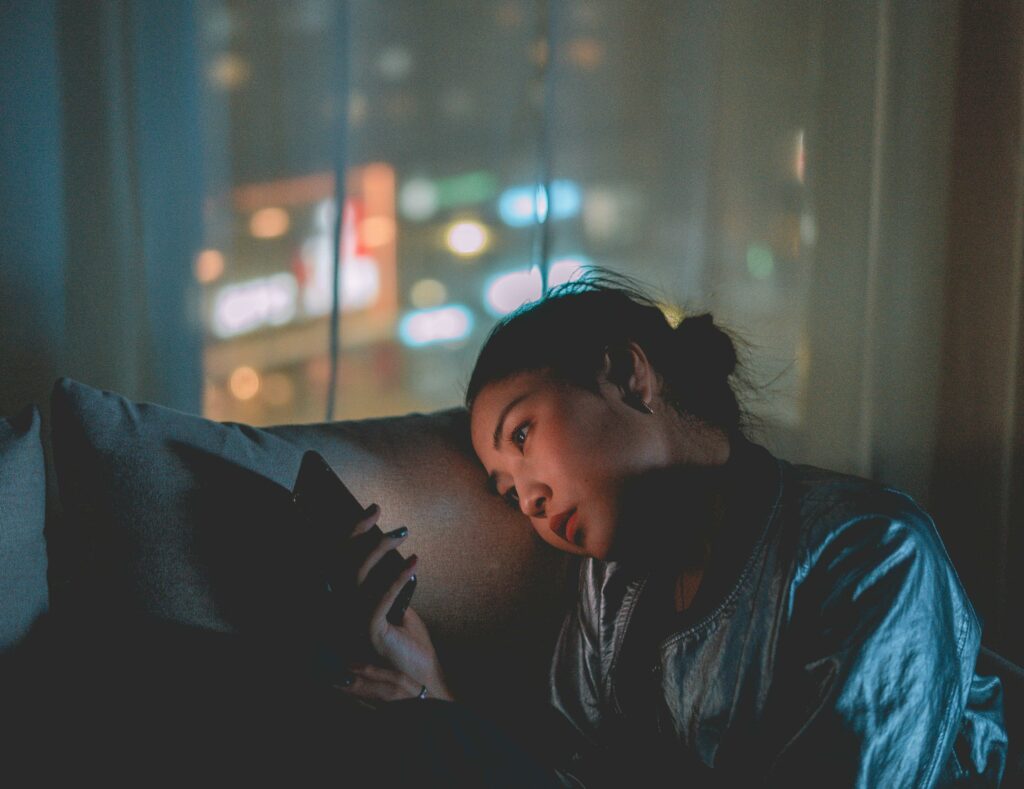 a woman lying on a couch looking at her phone