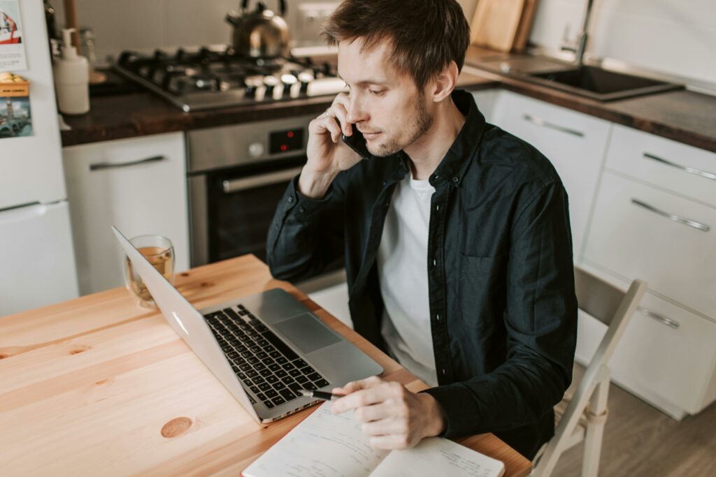 a man sitting at a table with a laptop and a phone