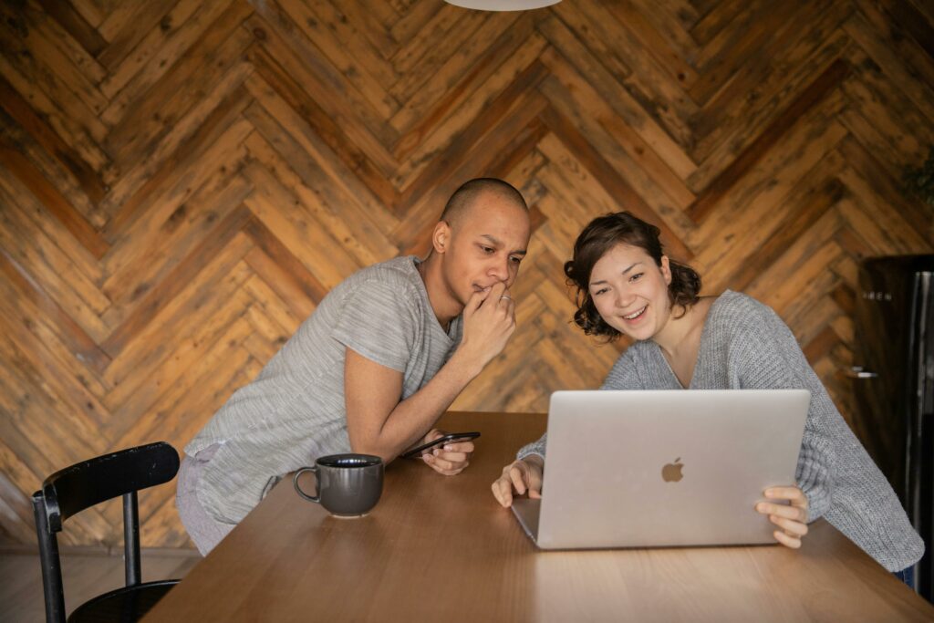 a man and woman sitting at a table with a laptop