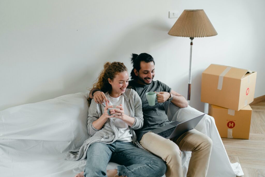 a man and woman sitting on a couch with a laptop