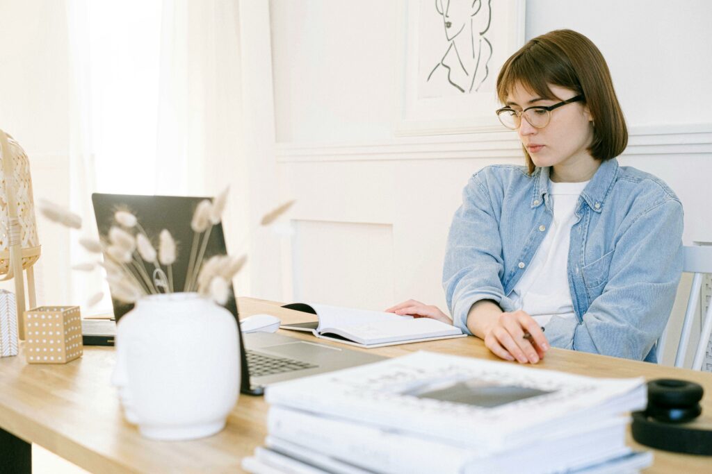 a woman sitting at a desk with a laptop and a book