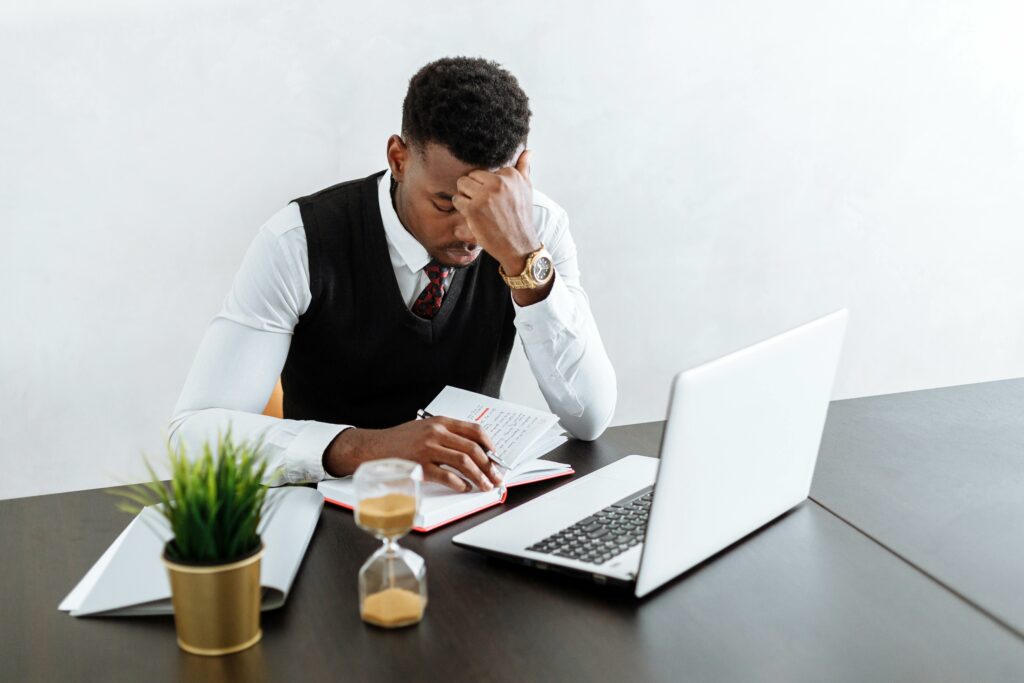 a man sitting at a desk with a laptop and a notebook