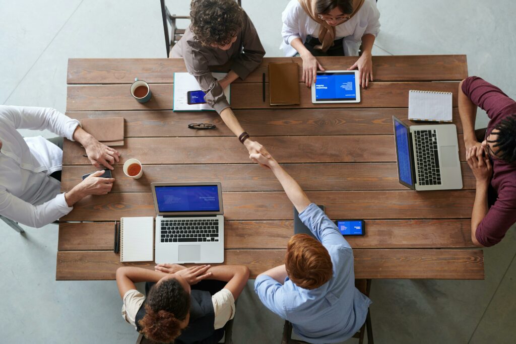 a group of people around a table with laptops and tablet computers