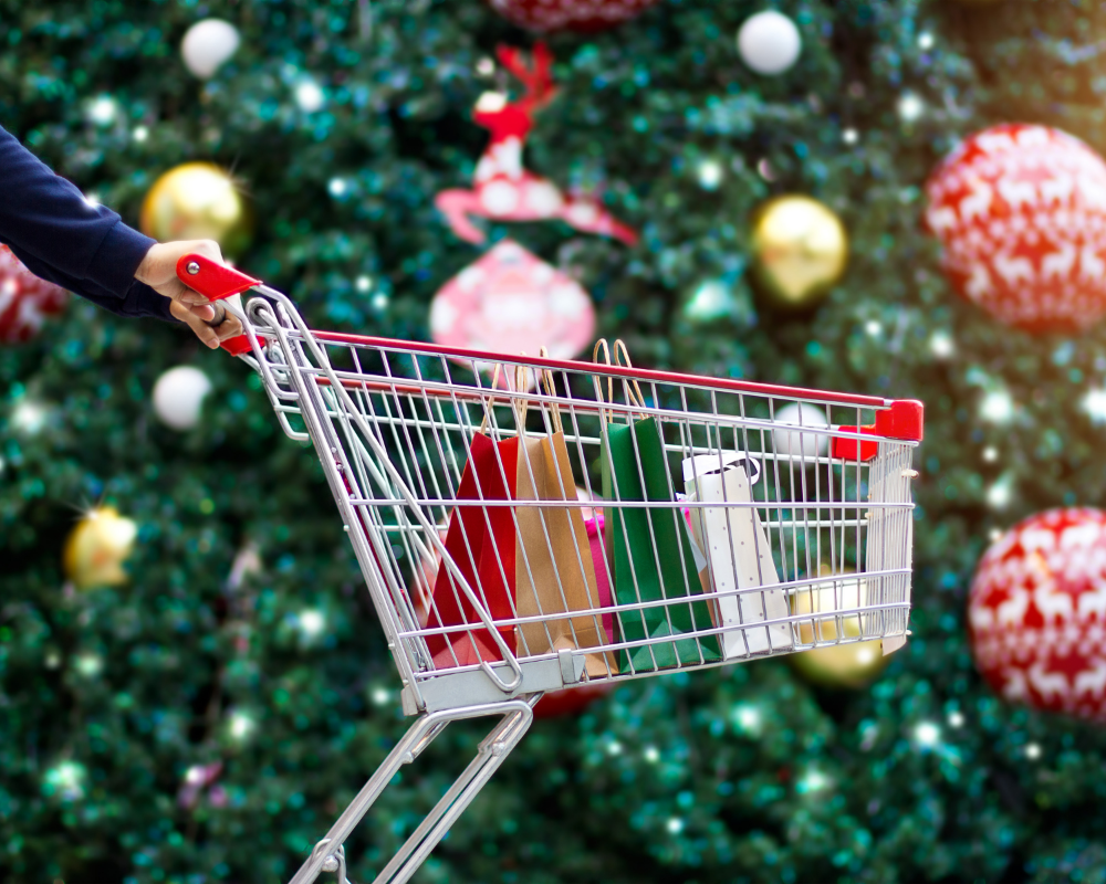 a person pushing a shopping cart with bags in front of a christmas tree