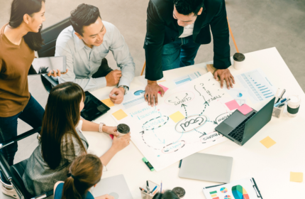 a group of people around a table looking at a diagram