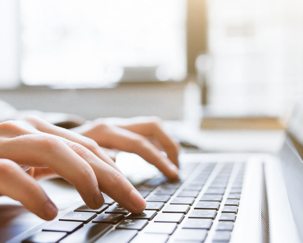 a person's hands typing on a laptop keyboard