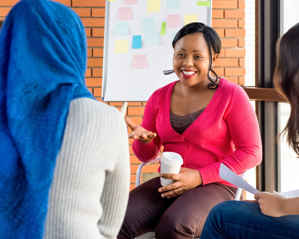 a woman sitting in a chair and talking to a group of people