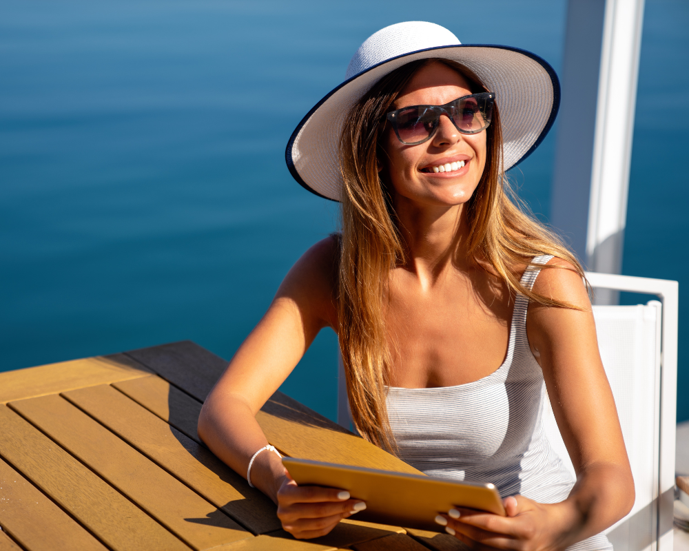 a woman wearing a hat and sunglasses sitting at a table