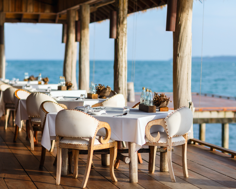 a table set up on a deck with a view of the ocean