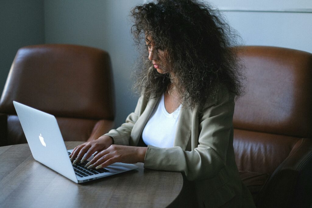 a woman sitting at a table typing on a laptop